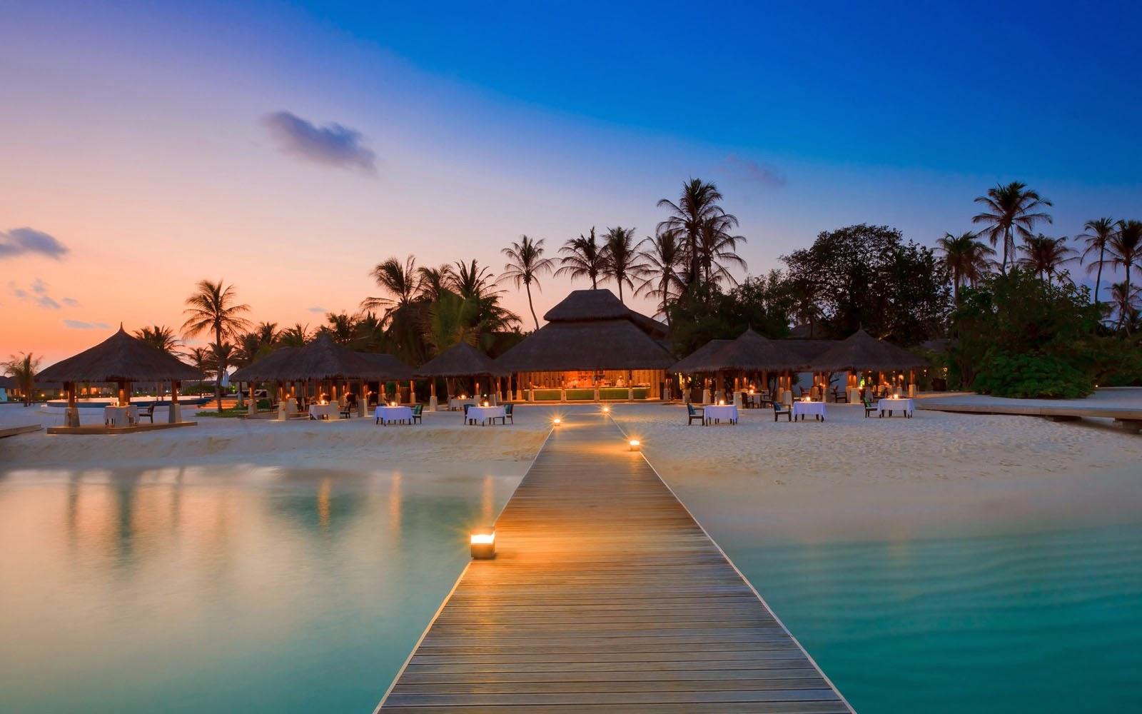 Maldives resort pier at sunset with palm trees and turquoise water