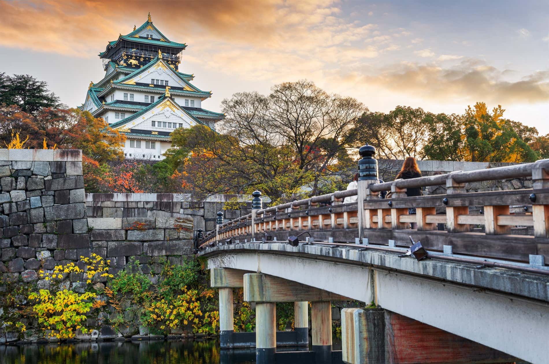 Osaka Castle with bridge and autumn trees at sunset